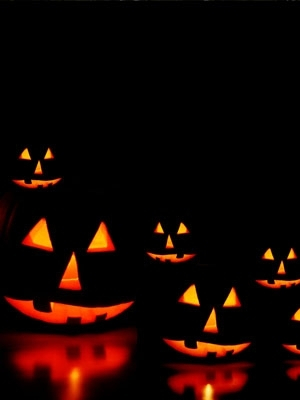 Five lit Jack-O-Lanterns in a black background